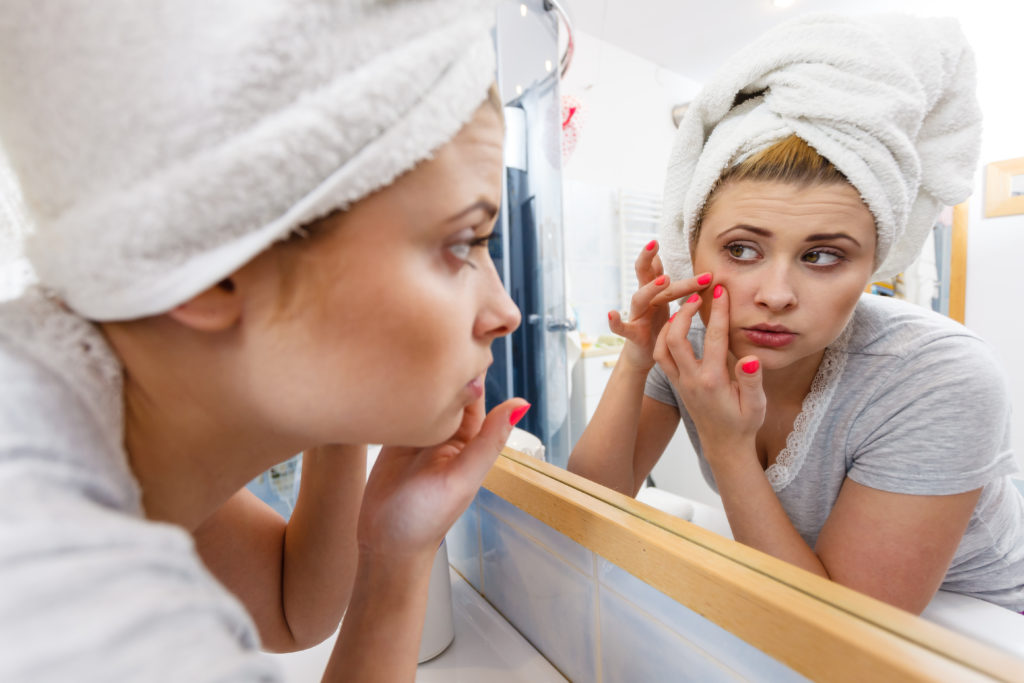 Canva Woman Looking In Mirror Dealing With Acne 1 1024x683